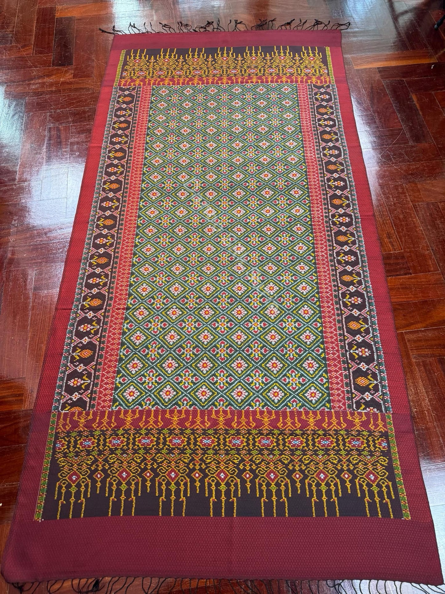 Mudmee silk sarong, woven with 6 tassels, frame work, size 1x2 meters, with a frieze on the front of a woman, red background, code L9A-DN-06156708443.